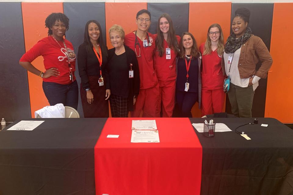Ladun Olateru-Olagbegi standing with other nurses in front of a black and red table.