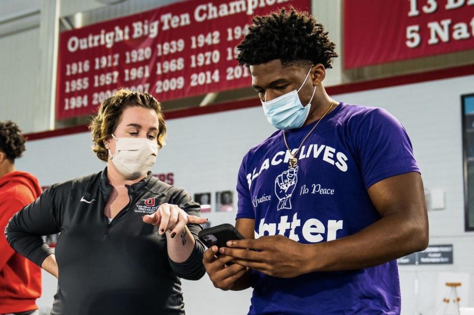 AJ Johnson in a gymnasium helping an Ohio State football team member register to vote on their phone.