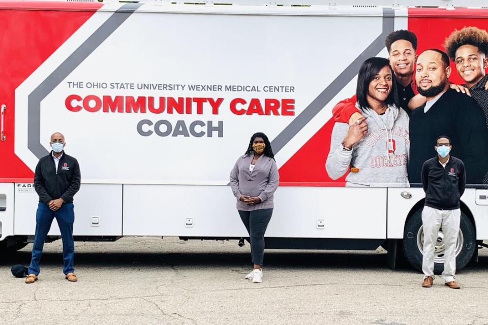 Darrell Gray, Joshua Joseph and Timiya Nolan standing in front of the Community Care Coach.
