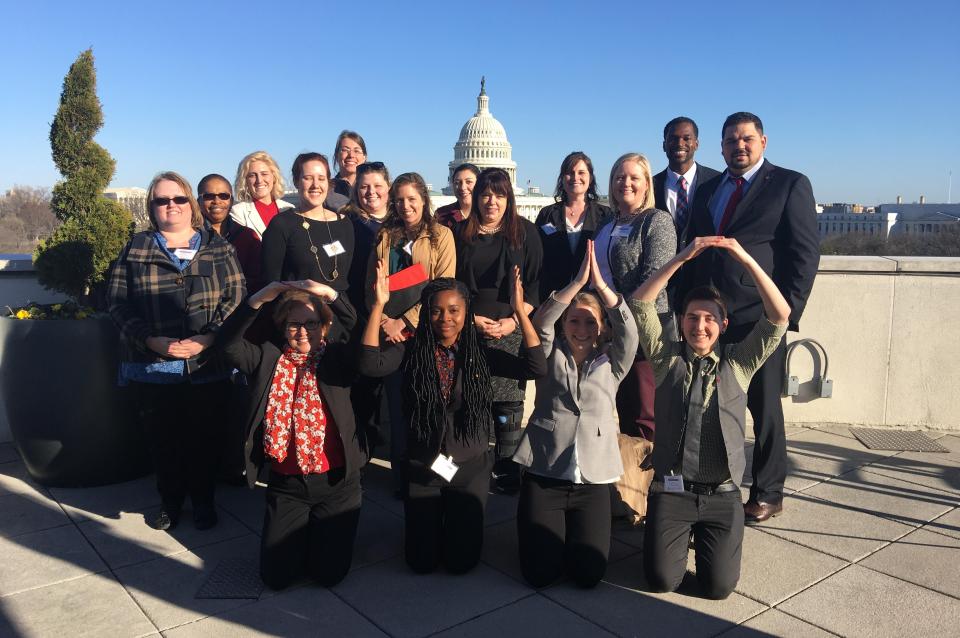 Lisa Durham posing with students in front of the US Capitol building. Students in front are spelling out O-H-I-O with their arms.