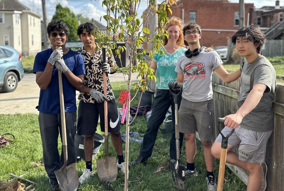 Paula Meijerink and four young men planting a tree.