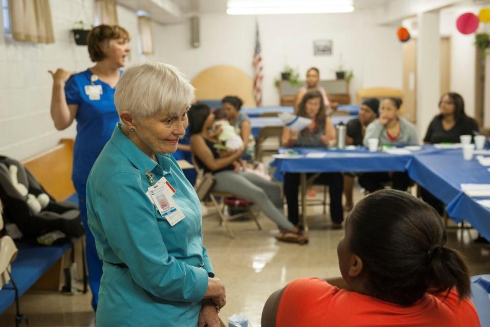 Patricia Gabbe speaking to a woman in a healthcare setting.