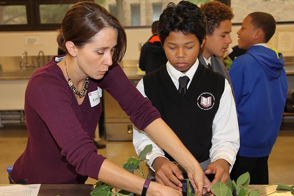 Courtney price standing next to a student with plants in a classroom.