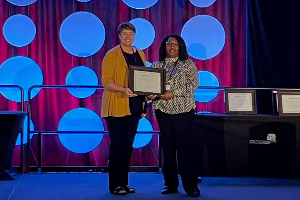 Shaunta Stanford standing on a stage accepting an award.